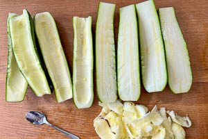 Zucchini waschen, halbieren und Fruchtfleisch herausl&ouml;ffeln