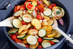 Tomaten, Zucchini und Knoblauch hinzugeben und würzen