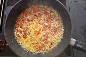 Zwiebel- und Knoblauchwürfel in die Pfanne geben